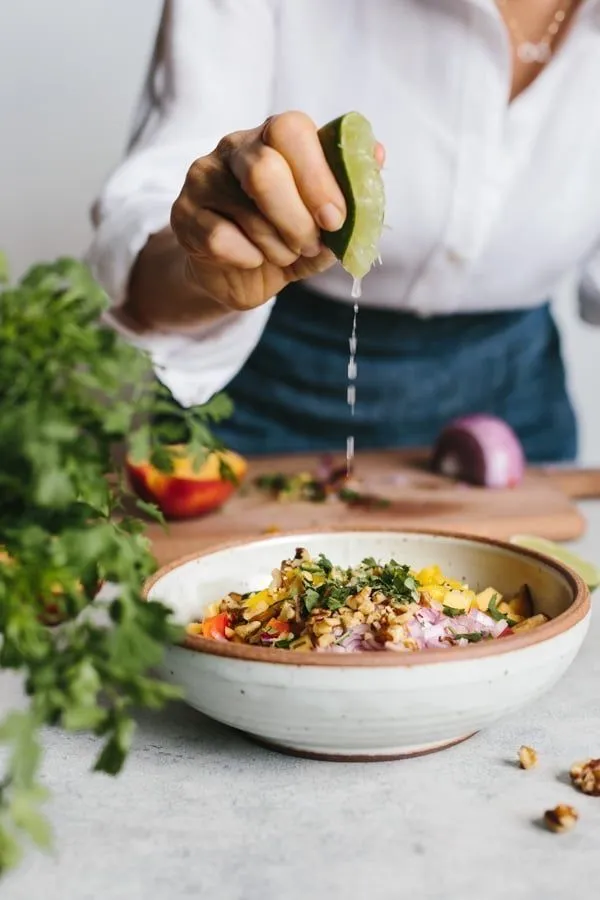 Mãos preparando uma salada fresca com limão