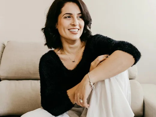 Mulher sentada no sofá, tranquila e sorrindo